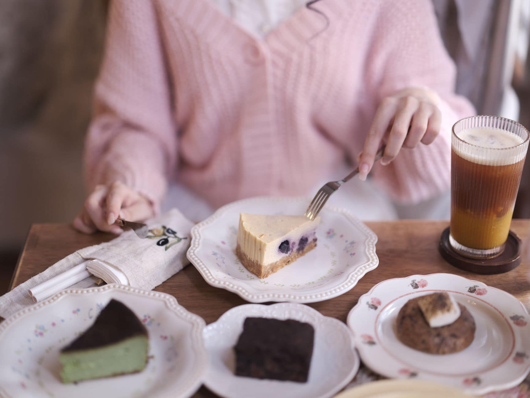 Indulge in a variety of desserts with a refreshing iced coffee, featuring cheesecake, brownies, and cookies.