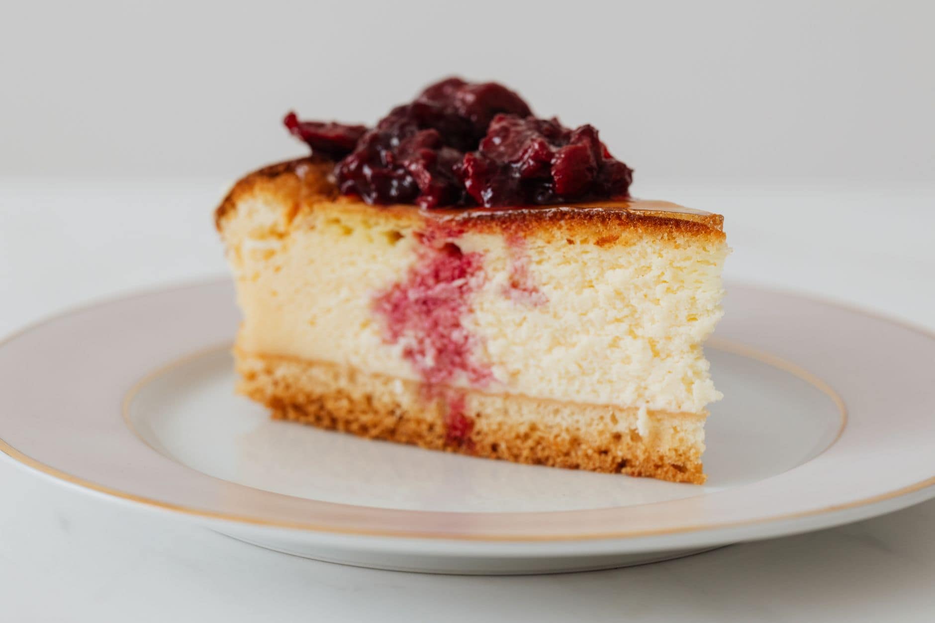 Closeup of piece of yummy homemade cheesecake with berries in syrup on top served on plate