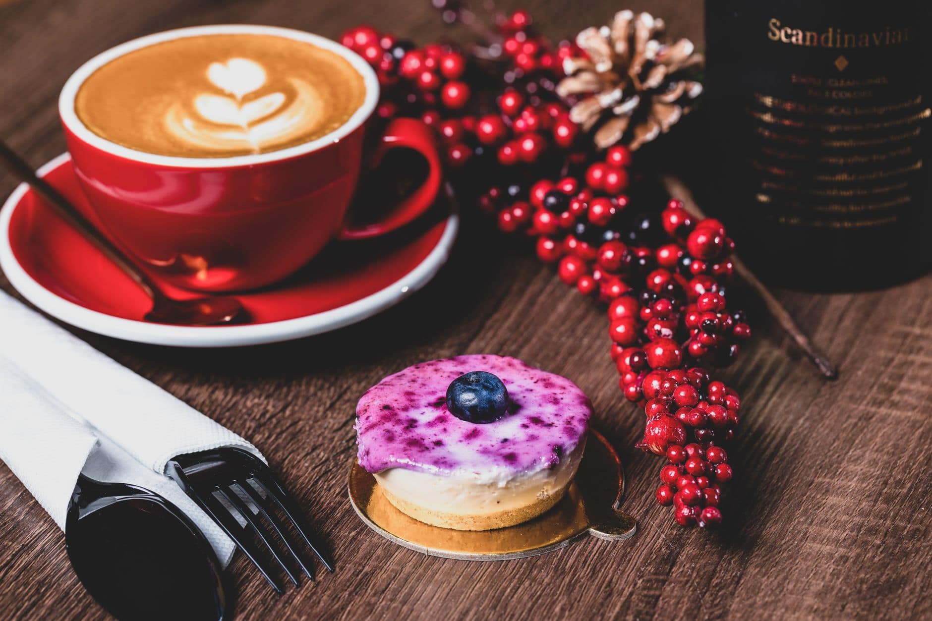 Latte art coffee with cheesecake topped with blueberries, perfect breakfast treat.