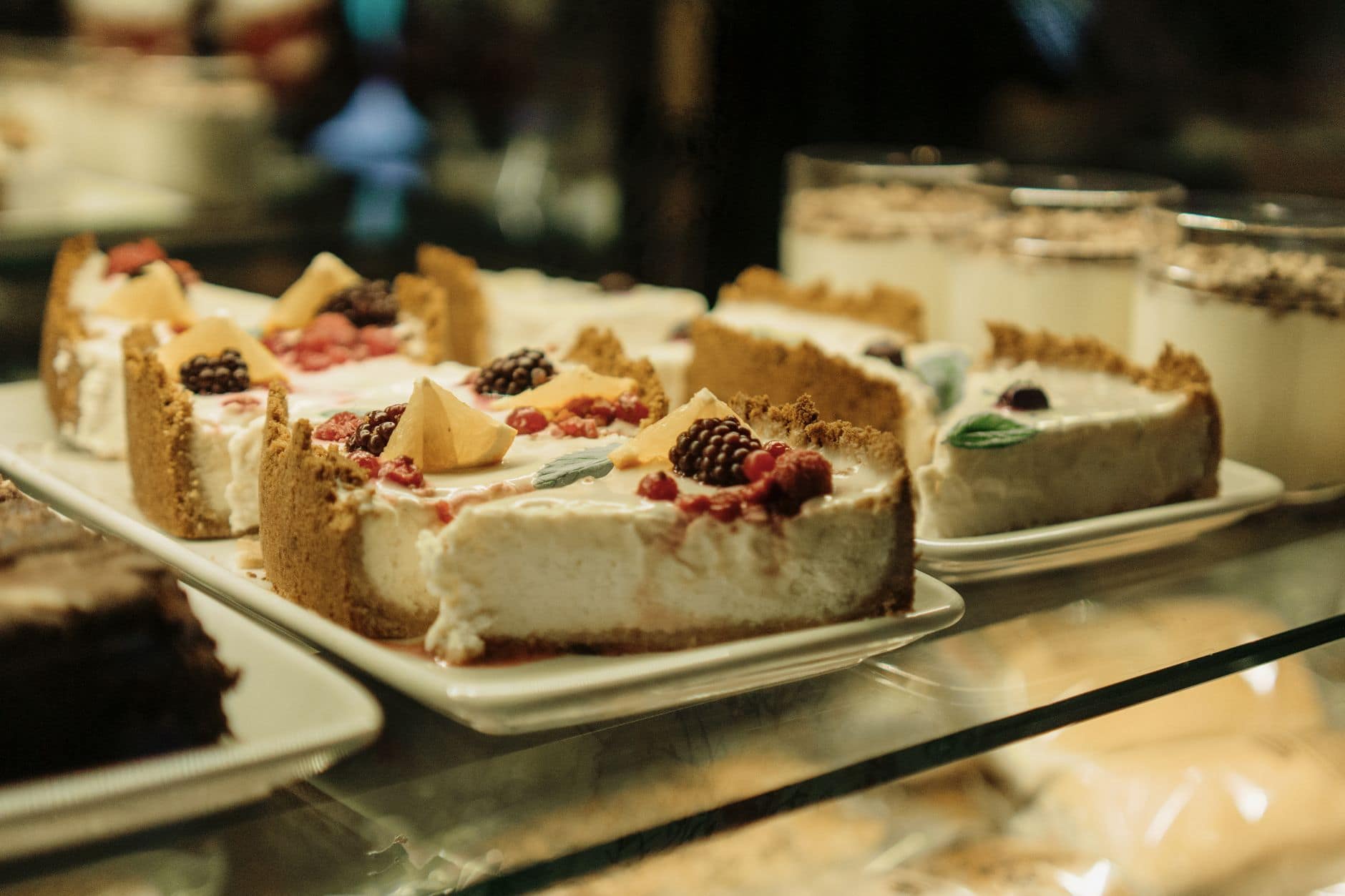 Enticing cheesecake slices with berries displayed in a glass showcase, perfect for dessert lovers.